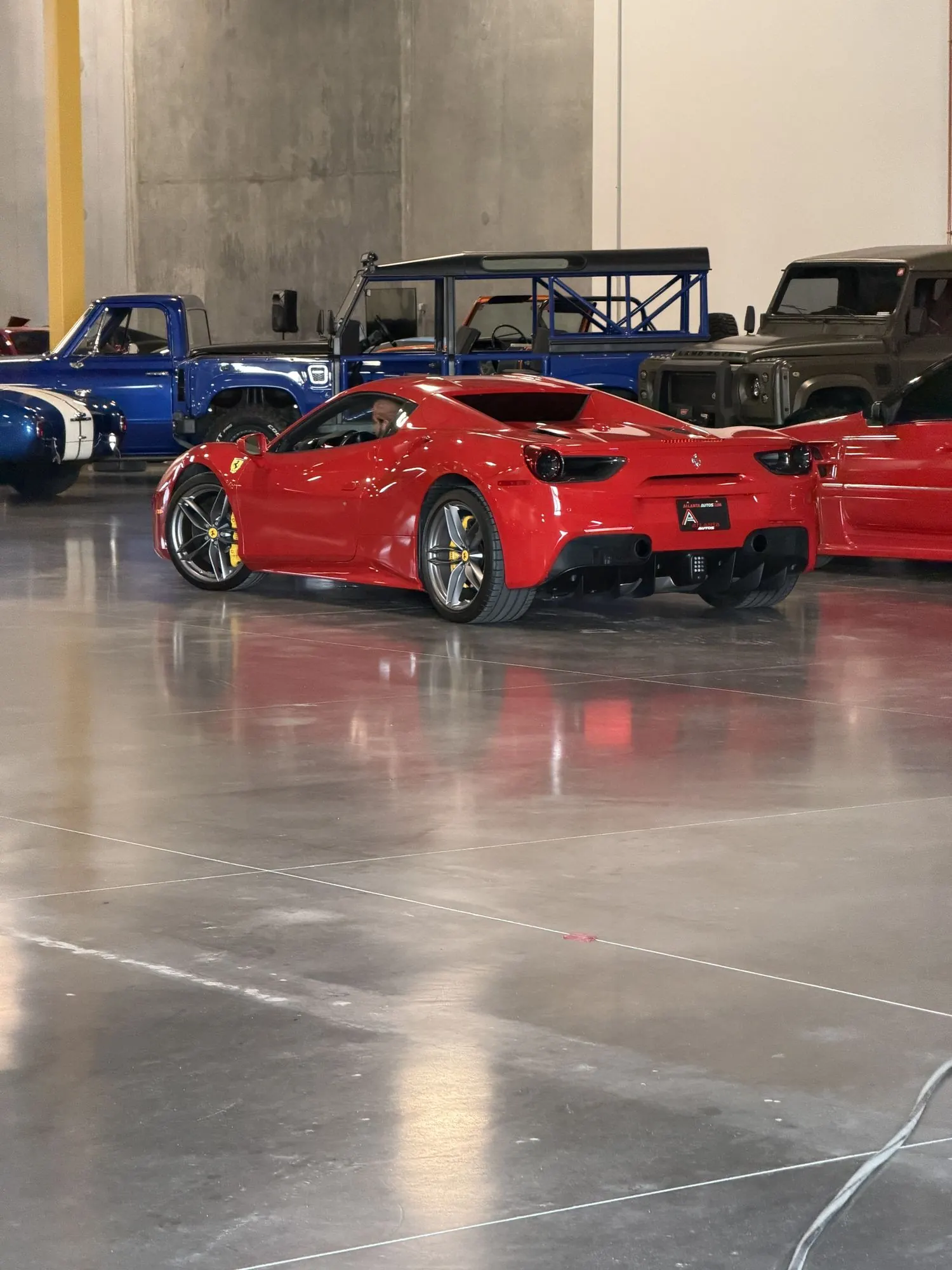 Red Ferrari 488 on the floor with Defenders and exotics